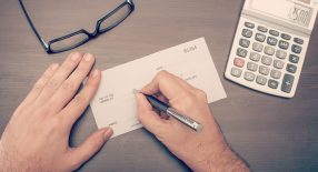 a person with a pen and a calculator on a desk.